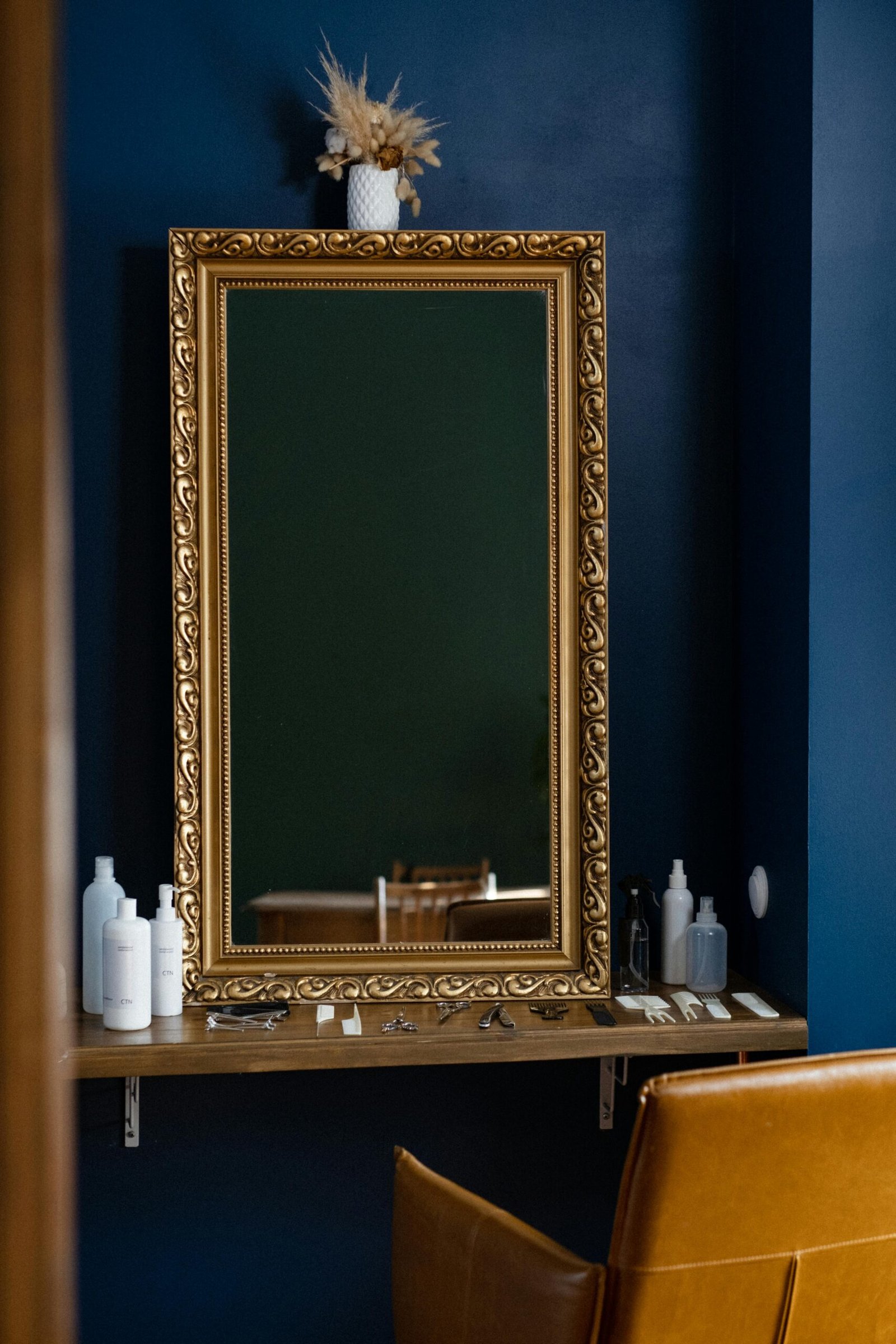 Stylish salon space featuring a decorative mirror and grooming products on a wooden shelf.
